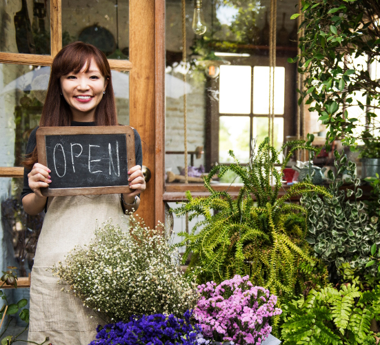 woman holding open sign on chalkboard